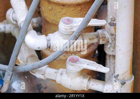 Vecchi rubinetti di plastica sporchi sul tubo. Vecchio impianto idraulico. Messa a fuoco selettiva Foto Stock