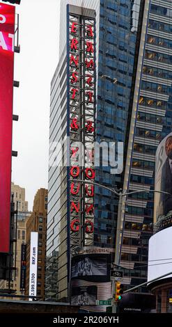 Segno rosso al neon di Ernst & Young, riflesso nella facciata in vetro di Five Times Square, all'angolo sud-ovest di Broadway e West 42nd Street. Foto Stock