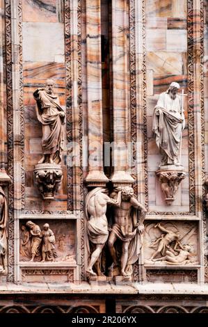 Bassorilievo statue di santi e martiri e pannelli di marmo con storie bibliche, Duomo di Milano, Italia. Foto Stock