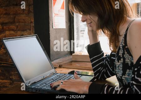 giovane transgender donna latina imprenditore di etnia argentina, seduto a lavorare con il suo laptop, controllare i guadagni, navigare in internet, analyzi Foto Stock