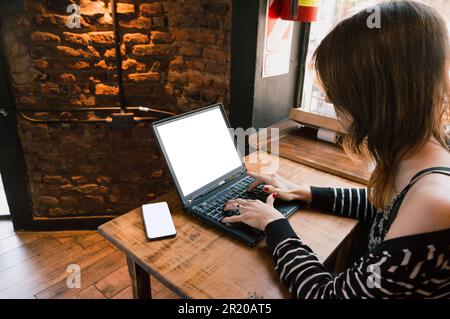 giovane donna transgender latina di etnia argentina, seduta con il suo portatile in un ristorante, digitando sulla tastiera, rispondendo alle e-mail, con il ph Foto Stock