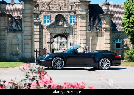 Donna con Porsche 911 cabriolet di fronte al castello, Porsche Carrera 4S Cabriolet, convertibile, auto sportiva Foto Stock