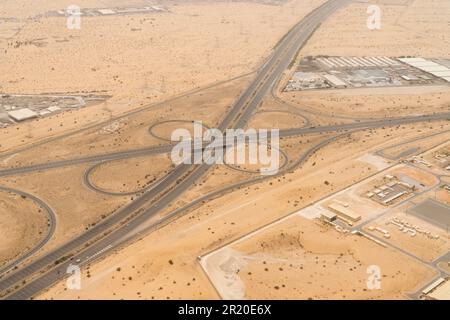 Veduta aerea di un'autostrada con un elevato interscambio in un paesaggio desertico a Dubai, Emirati Arabi Uniti. Foto Stock