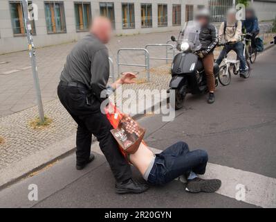 16 maggio 2023, Berlino: Durante un blocco di strada dell'ultima generazione, un passerby tira fuori dalla strada un attivista. Foto: Paul Zinken/dpa - ATTENZIONE: Le persone sono state pixelate per motivi legali Foto Stock