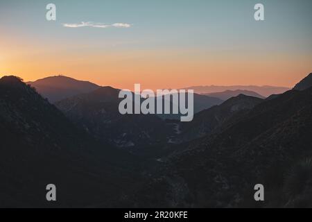 Un tramonto mozzafiato su un crinale di montagna, con le silhouette di cespugli sullo sfondo della montagna ombrosa Foto Stock