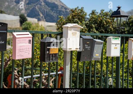 varie cassette postali colorate lungo il lato della strada Foto Stock