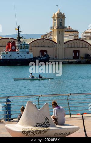 canoa nel porto con una barca da pesca sullo sfondo e gli edifici con i numeri 12 e 11 Foto Stock