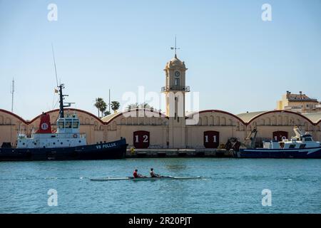 canoa nel porto con una barca da pesca sullo sfondo e gli edifici con i numeri 12 e 11 Foto Stock