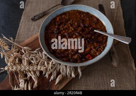 Stufato di fagioli di rene con manzo macinato, al forno, fagioli, peperoni, cipolle, erbe all'aglio, pomodori su un piatto Foto Stock