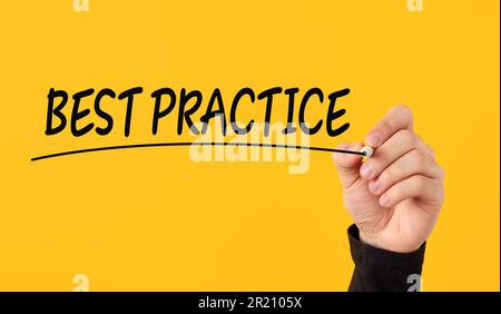 Best practice nel concetto aziendale. La mano maschile disegna una linea sotto la parola Best practice su sfondo giallo. Foto Stock