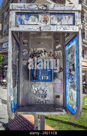 Salonicco, Grecia, 27 aprile 2023: Cassetta telefonica pubblica piena di adesivi e di vernice scrawling nel centro della città di Salonicco in una giornata di sole Foto Stock