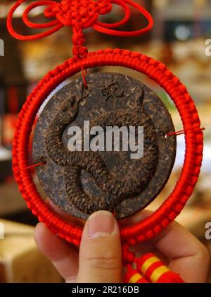 Tè secco compresso che mostra un motivo di un serpente in vendita presso un mercato di strada di Kunming, Kunming, provincia di Yunnan, Cina Foto Stock