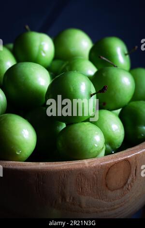 Prugne verdi fresche in ciotola su fondo di legno. Primo piano. Foto Stock