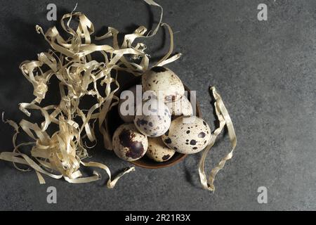 Uova di quaglia, uova di quaglia fresche e piume sul fondo del tavolo, guscio d'uovo di uova crude Foto Stock