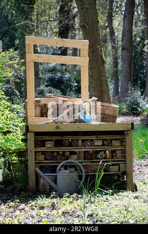 Bug hotel in una struttura in legno. Vecchie lattine di annaffiatura e foresta Foto Stock