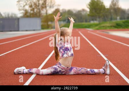 Una ragazza in un legging che fa si divide allo stadio Foto Stock