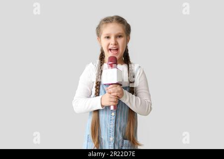 Bambina con microfono su sfondo chiaro. Festa dei bambini Foto Stock