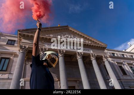 Madrid, Spagna. 16th maggio, 2023. Un vigile del fuoco tiene un bagliore di fumo durante la manifestazione di fronte al Congresso spagnolo. Dimostrazione dei vigili del fuoco spagnoli organizzata dalla Professional Firefighters Union (CUBP). I vigili del fuoco hanno annunciato che chiederanno l'approvazione di una legge quadro che distingua le loro funzioni e poteri, poiché hanno assicurato che attualmente ci sono molte comunità autonome che non hanno leggi che regolano la loro attività, lasciandole non protette. Credit: SOPA Images Limited/Alamy Live News Foto Stock