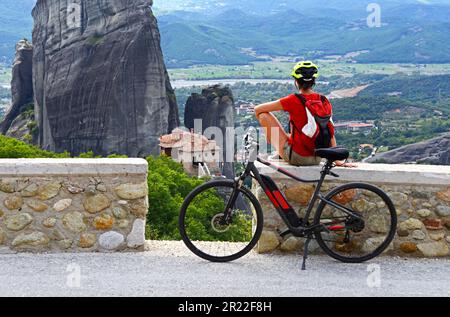 Donna con e-bike sulle Meteors, guardando il monastero Roussanou , Grecia, Tessaglia Foto Stock