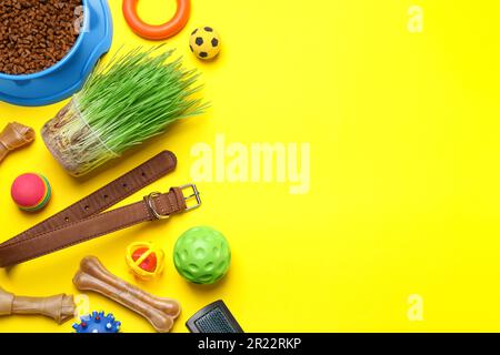 Composizione piatta con giocattoli per animali domestici, accessori e ciotola di cibo su sfondo giallo, spazio per il testo Foto Stock