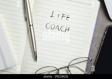 Phrase Life Coach scritto in notebook, penna e bicchieri sul tavolo, vista dall'alto Foto Stock