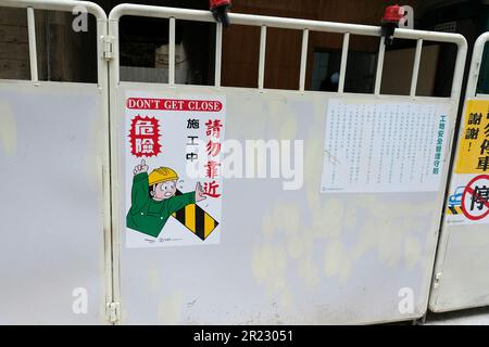 Non fatevi un cartello vicino su una barriera che avverte i pedoni del pericolo di caduta di oggetti in un cantiere di Taipei, Taiwan; zona dell'elmetto. Foto Stock