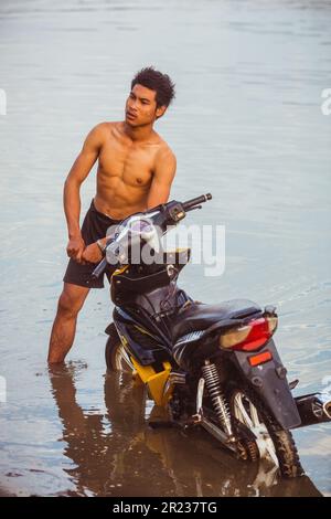 Myanmar, 18 febbraio 2021: Un uomo locale sta lavando la sua bicicletta nel fiume. Foto Stock