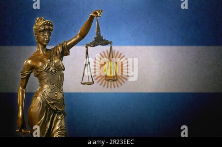 Primo piano di una piccola statuetta di bronzo di Lady Justice davanti a una bandiera argentina. Foto Stock