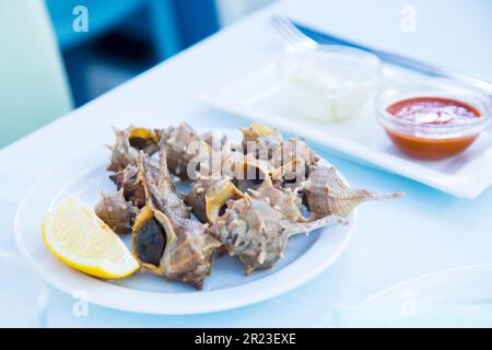 Lumache di mare grigliate in un ristorante spagnolo di tapas. Foto Stock