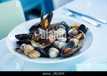 Piatto con una varietà di frutti di mare come cozze, vongole e lumache di mare. Tapa di pesce spagnolo. Foto Stock