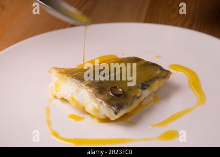 Bacalao al Pil Pil tradizionale tapa dal nord della Spagna. Baccalà cucinato con una deliziosa salsa fatta con olio, baccalà e aglio. Foto Stock