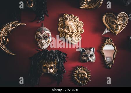 Un primo piano di maschere appese su una parete rossa Foto Stock