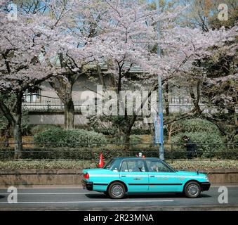 Tokyo, Giappone - 7 aprile 2019. Un taxi blu è parcheggiato per le strade di Tokyo in mezzo alla fioritura dei ciliegi in piena fioritura in primavera. Foto Stock