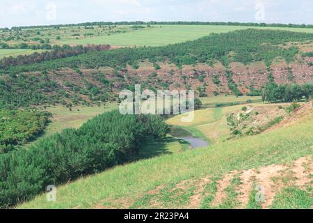 Verde valle lungo il fiume circondata da colline. Scenario di pascolo estivo Foto Stock