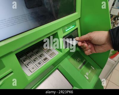 Primo piano della mano dell'uomo inserendo la e-card nello slot ATM Foto Stock