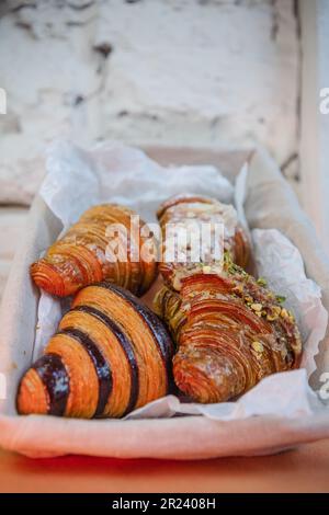 quattro tipi di croissant in un cestino su un tavolo bianco Foto Stock