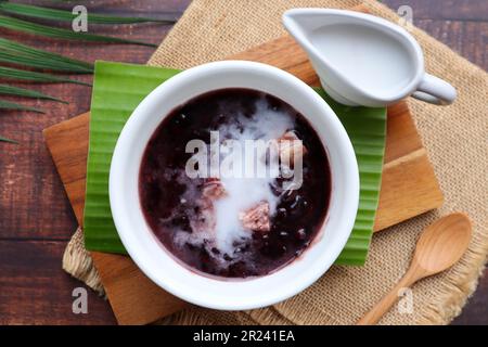 Budino di riso nero appiccicoso con taro e latte di cocco alla vista superiore della tavola di legno, riso glutinoso nero - dessert tailandese chiamato Khao Nieow Dam Foto Stock