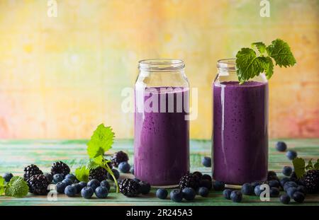 Frullato fresco di mora e mirtillo in bottiglie di vetro Foto Stock