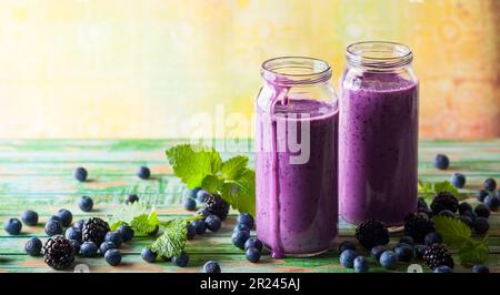 Frullato fresco di mora e mirtillo in bottiglie di vetro Foto Stock