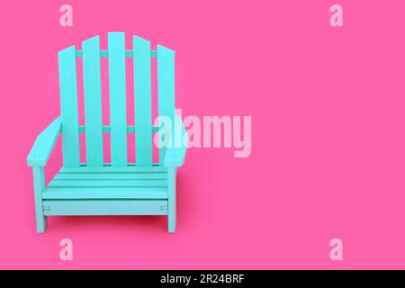 Concetto di tempo da solo con moderna sedia di legno blu su sfondo rosa brillante. Arredamento minimo, solitario, solitudine, tranquillo, concetto di contrasto. Foto Stock