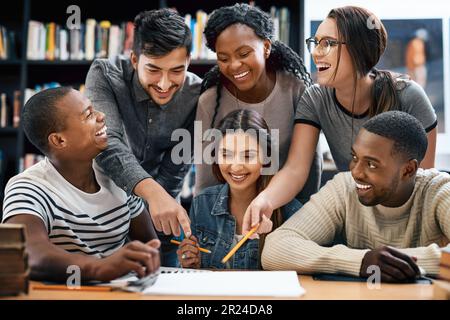 Gli studenti ridono in biblioteca, studiano insieme per esami o ricerche per progetti, istruzione e lavoro di squadra. Diversità, divertenti e giovani uomini con donne in Foto Stock