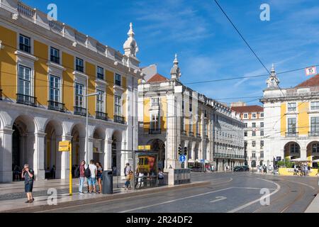 Lisbona, Portogallo-Ottobre 2022: Vista della fermata del tram su Praha do Comércio, piazza nel cuore della città, fiancheggiata da un tradizionale edificio di colore giallo Foto Stock