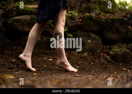 I piedi di una persona che cammina attraverso una foresta lussureggiante mentre Foto Stock