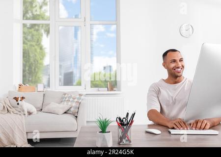 Giovane uomo con Jack Russell Terrier che lavora in ufficio a casa Foto Stock