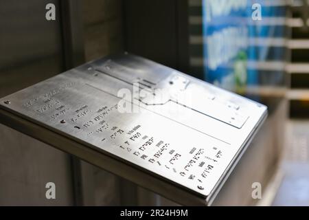 Stativo in argento con testo Braille e piano di costruzione al coperto, primo piano Foto Stock