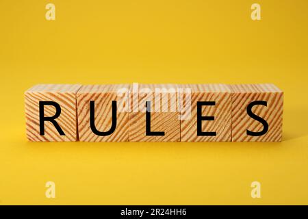 Regole di parola fatte di cubi di legno con lettere su sfondo giallo Foto Stock