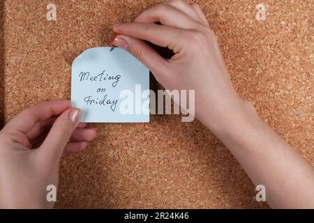 Donna pinning carta nota con frase riunione il Venerdì a sughero bordo, primo piano Foto Stock