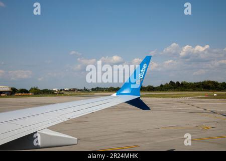 BUCAREST, ROMANIA - CIRCA 2022: Chiudi Visualizza il logo di Fly Dubai su ala di aereo. Vista dalla finestra dell'aeroplano che si prepara per il decollo sull'Aeroporto Otopeni. Foto Stock