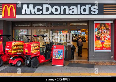 tokyo, giappone - aprile 11 2023: Motociclette a tre ruote giapponesi Honda Gyro Canopy utilizzate per McDelivery parcheggiate a McDonald's con un poster pubblicitario Foto Stock