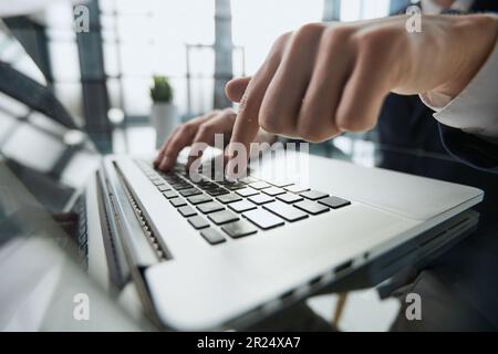 Giovane uomo preme il dito sul computer al tavolo in ufficio, primo piano. Foto Stock